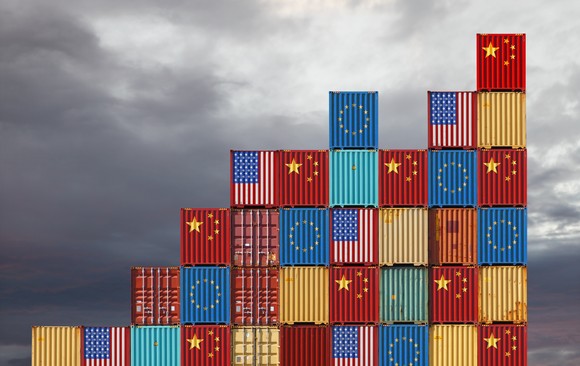 Stacked shipping containers marked with the U.S., European Union, and Chinese flags.