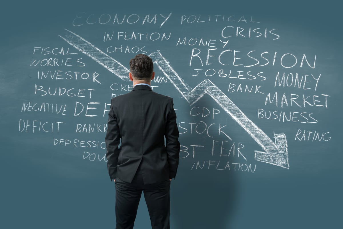 Person staring at downward arrow surrounded by words like Recession and Inflation.