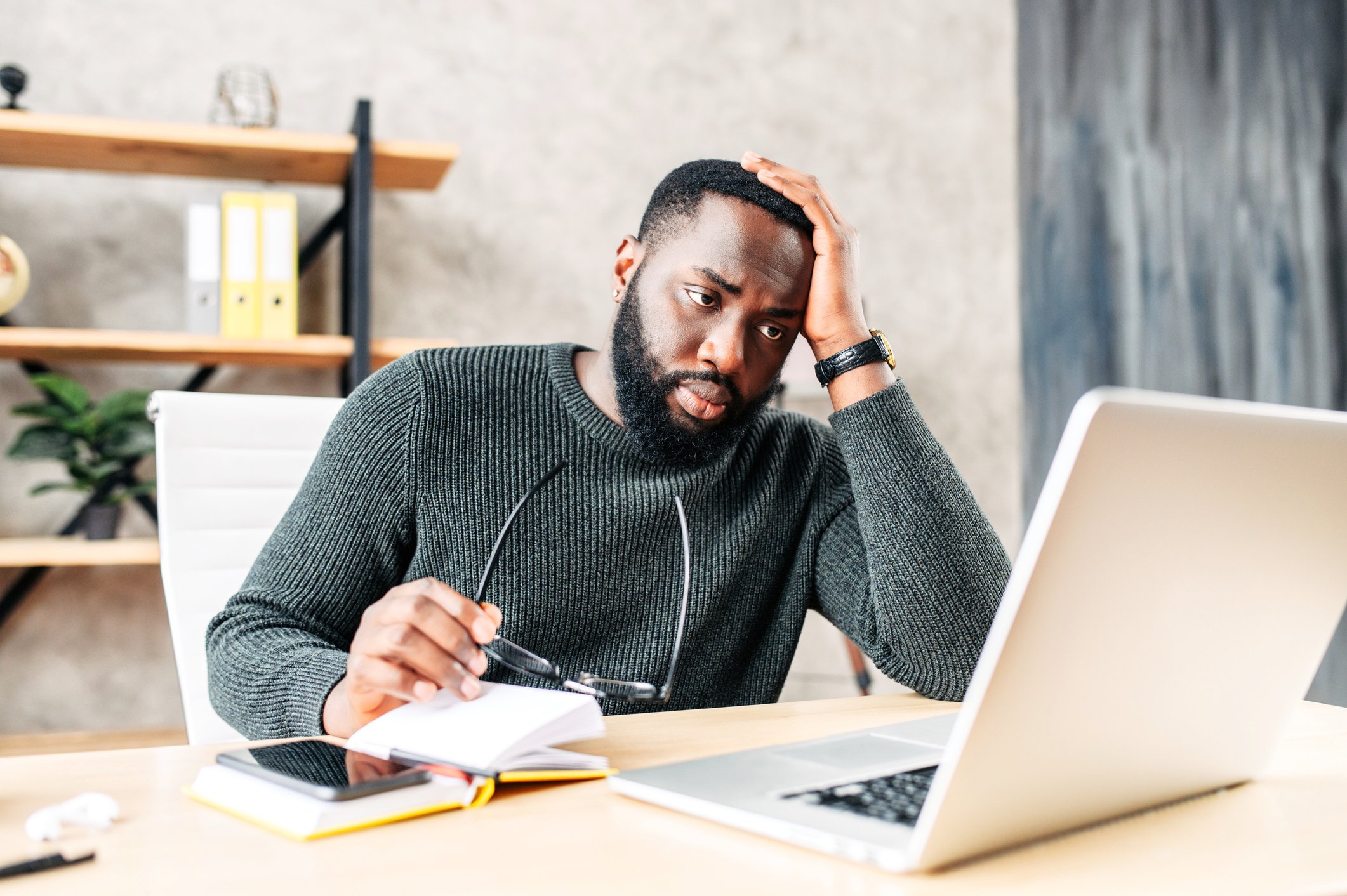 Person with a serious expression looking at a laptop.