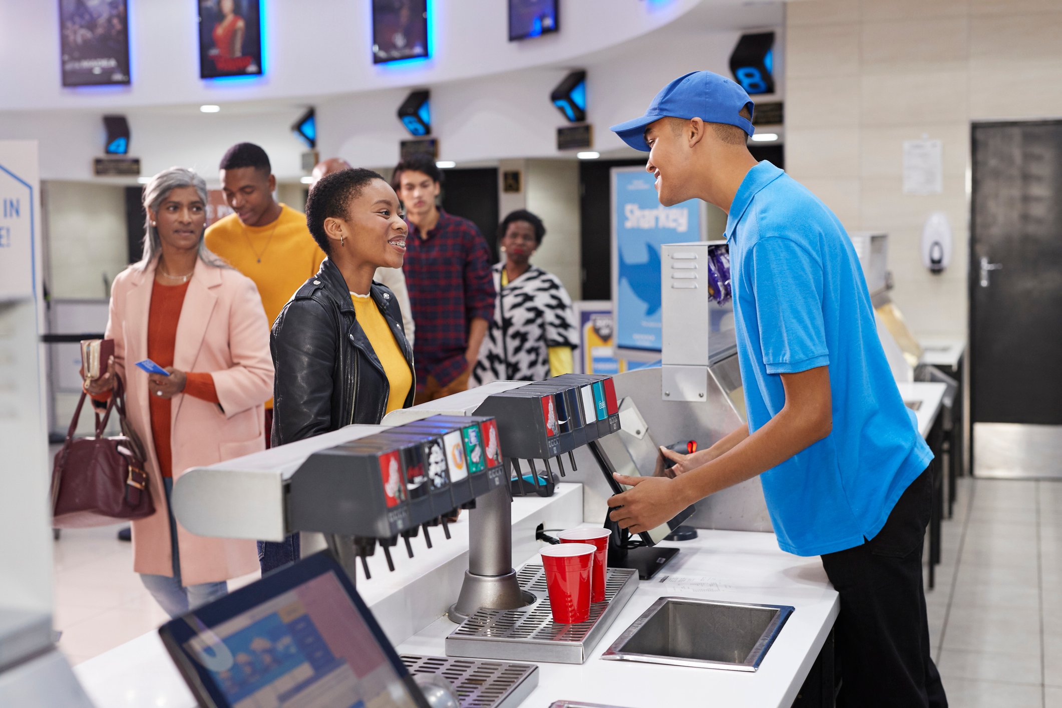Customers lining up for beverages at a movie theater's concessions stand.