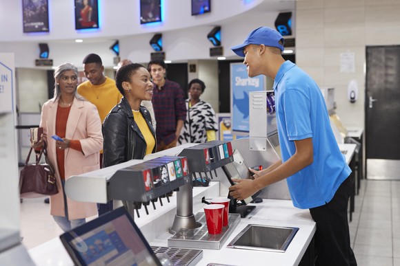 Customers lining up for beverages at a movie theater's concessions stand.