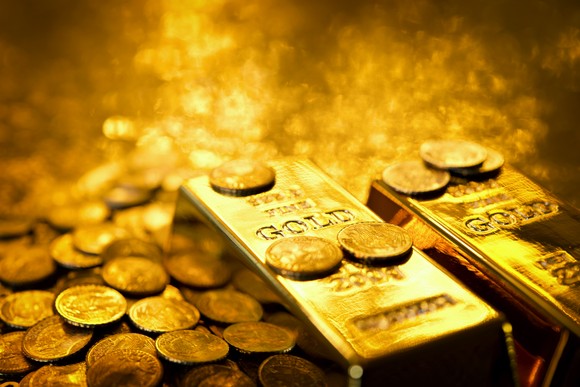 Gold bars and coins in golden light.