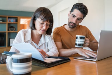 A couple using a laptop and reviewing documents.