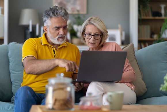 Couple in their 50s looking at a laptop.