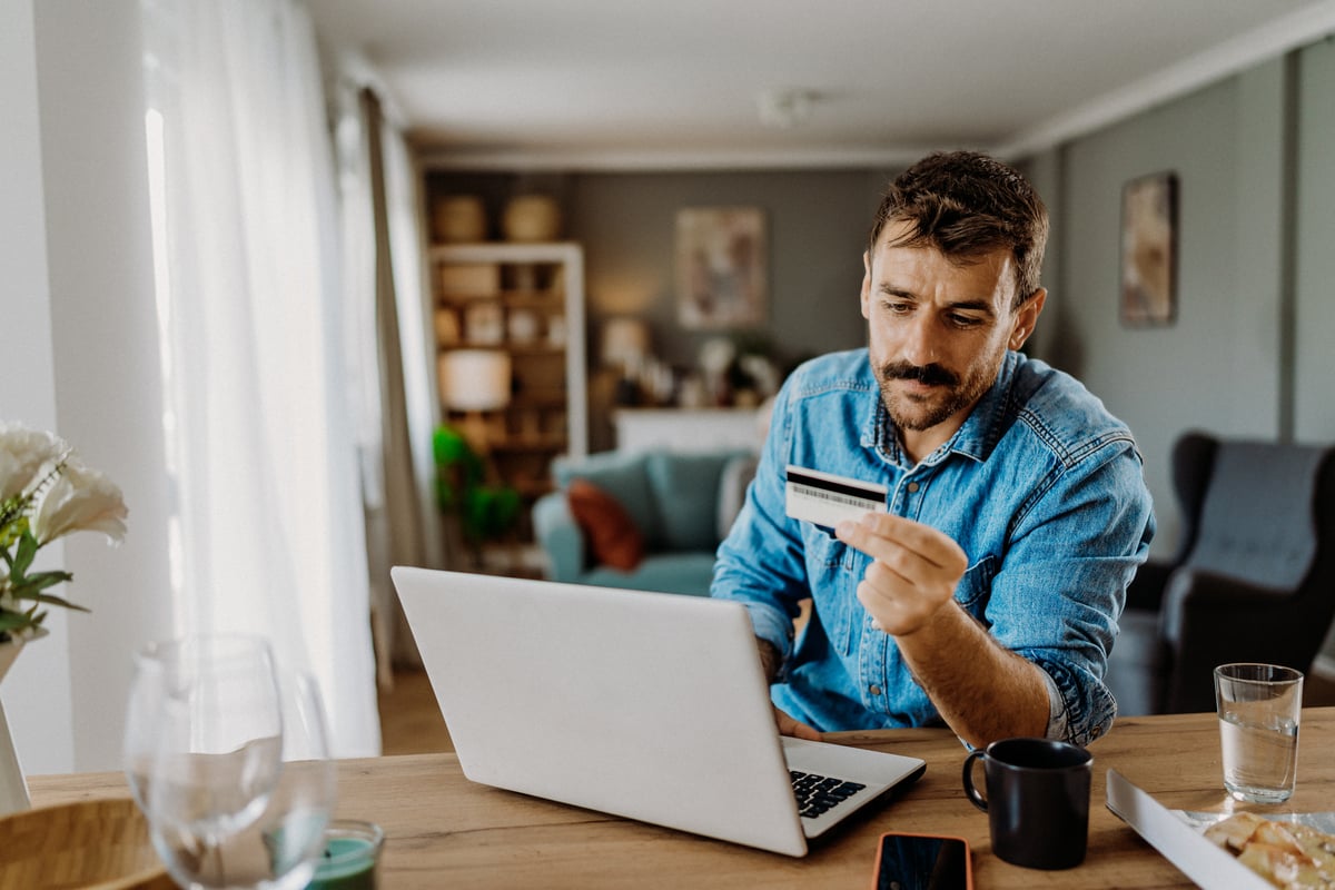 Person sitting at laptop and holding card.