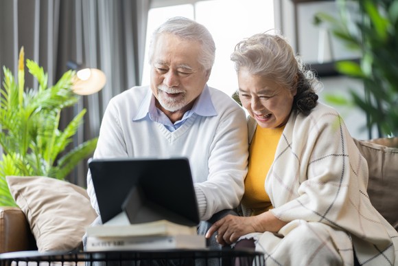 Two people sitting down and looking at a laptop.