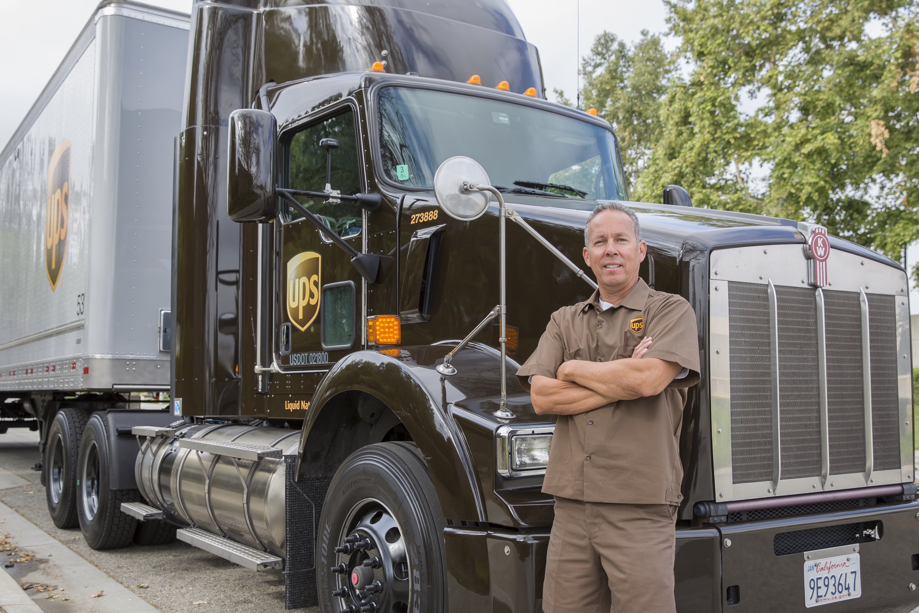 A smiling UPS driver stands near his rig.