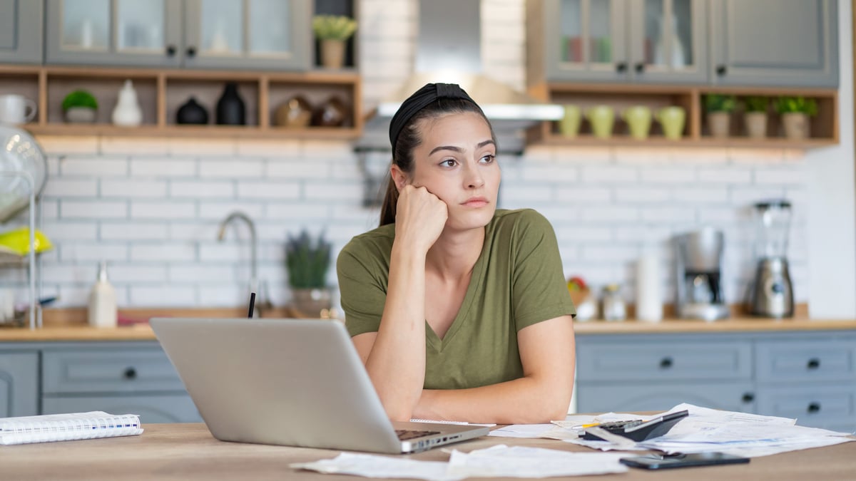 A person sits at a table with a laptop in front of them.