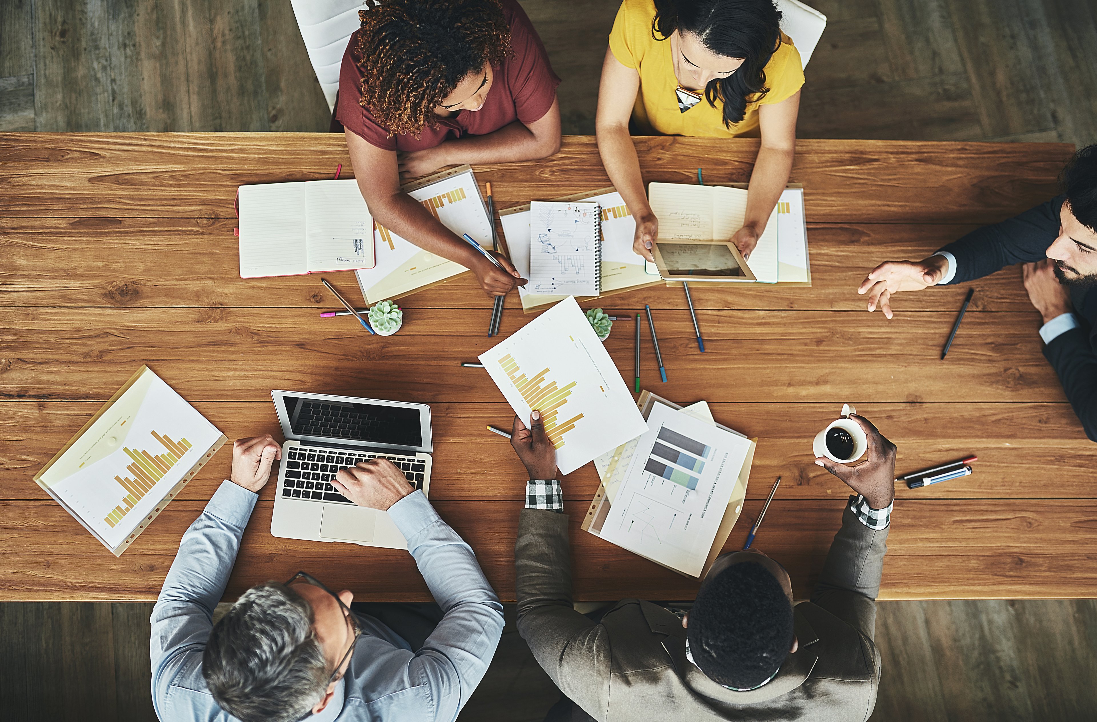 A group of people sitting around a long table looking at documents together.
