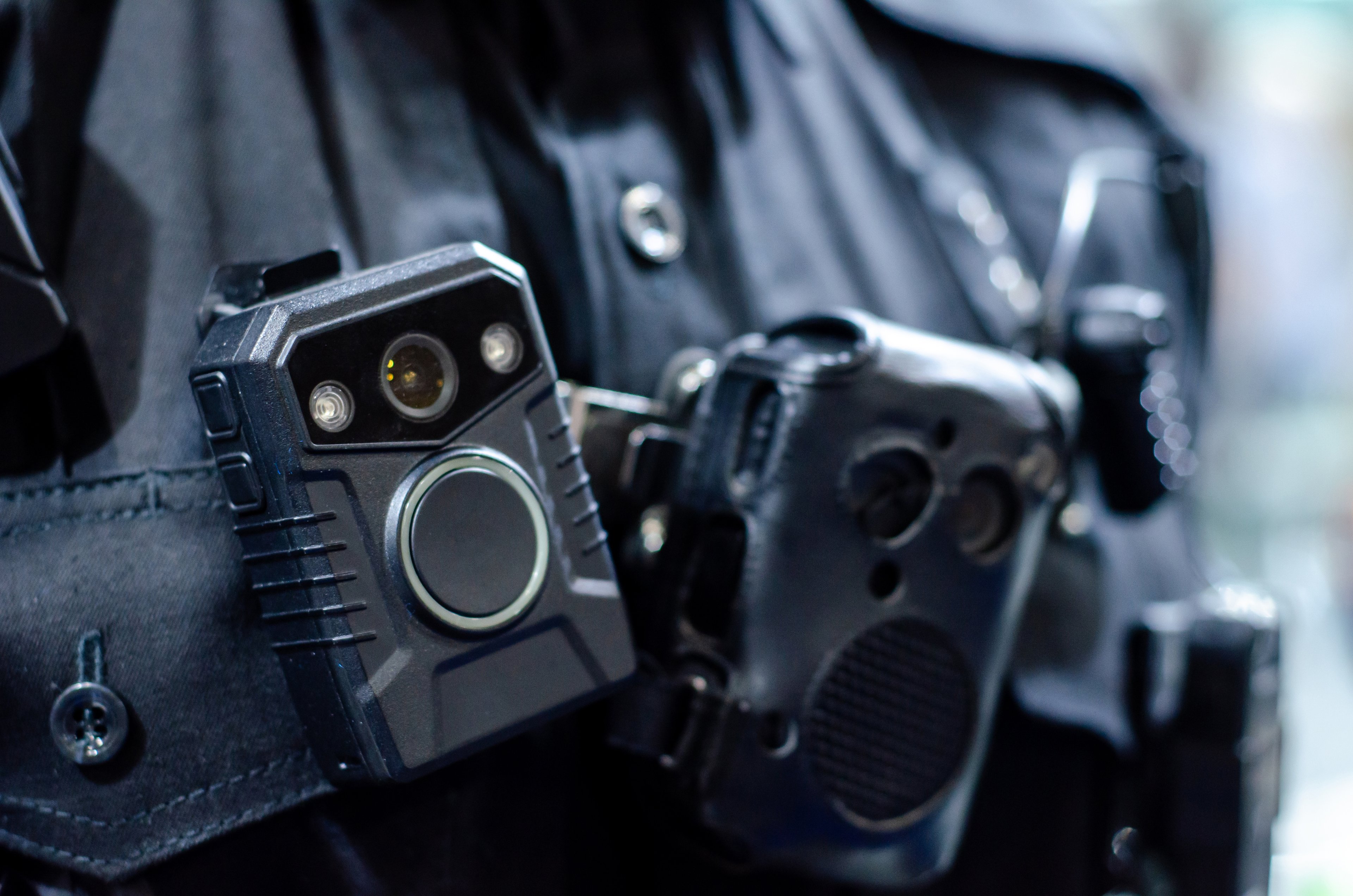 Close up shot of a police officer's chest, highlighting their body camera and walkie-talkie.