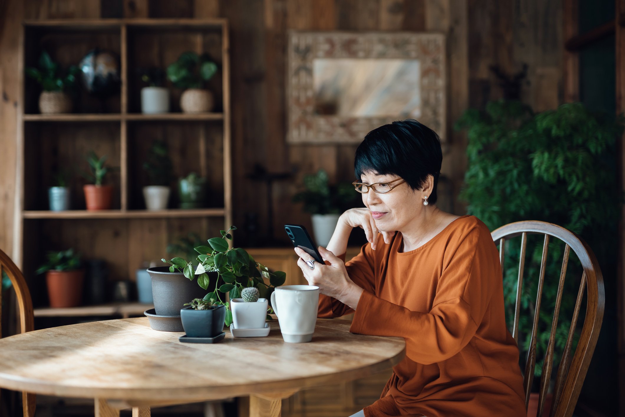 Person sitting at a table and looking at a phone.