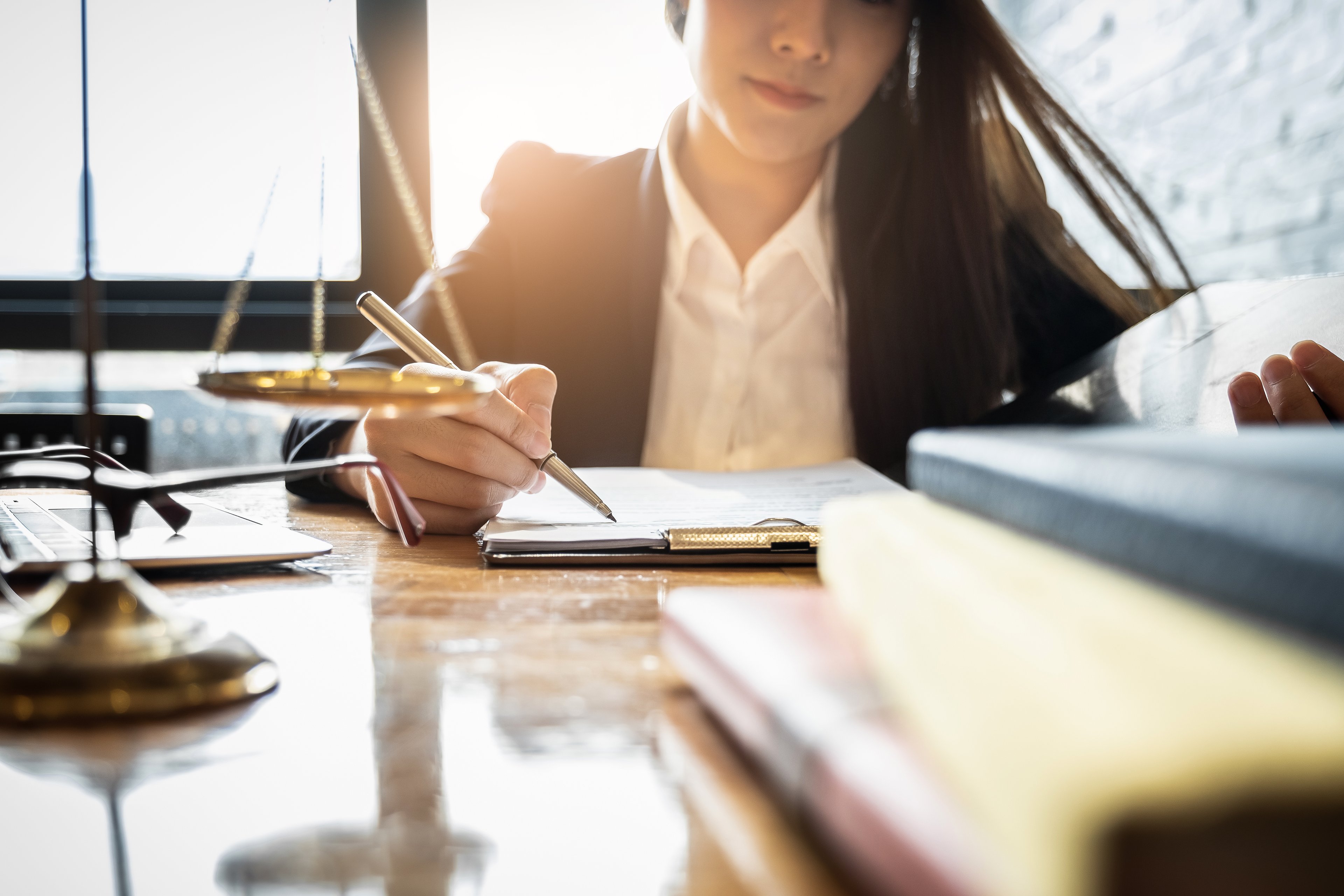 A person looks at paperwork at a desk holding a scale.