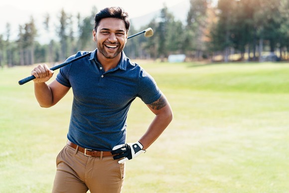 Smiling golfer on course with club. 
