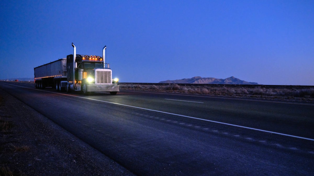 A semi truck on the road at dusk.