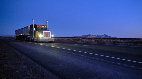 A semi truck on the road at dusk.