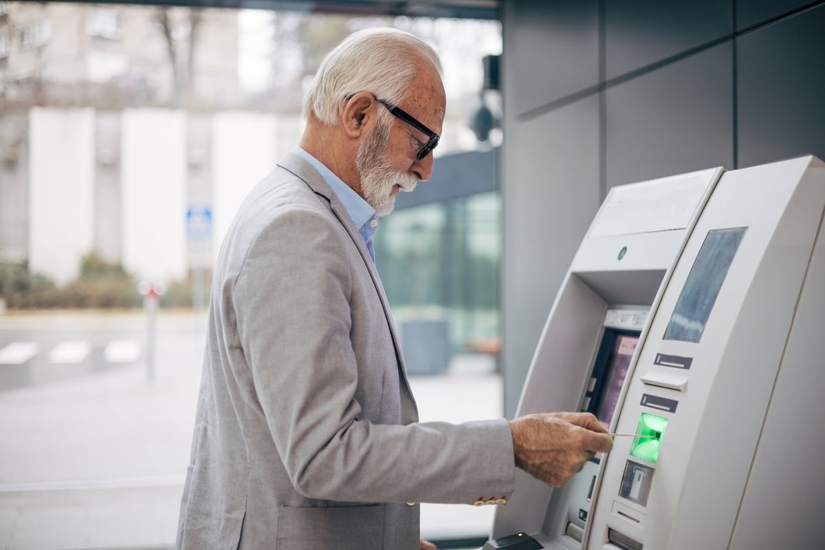 Person in business attire interacting with an ATM.