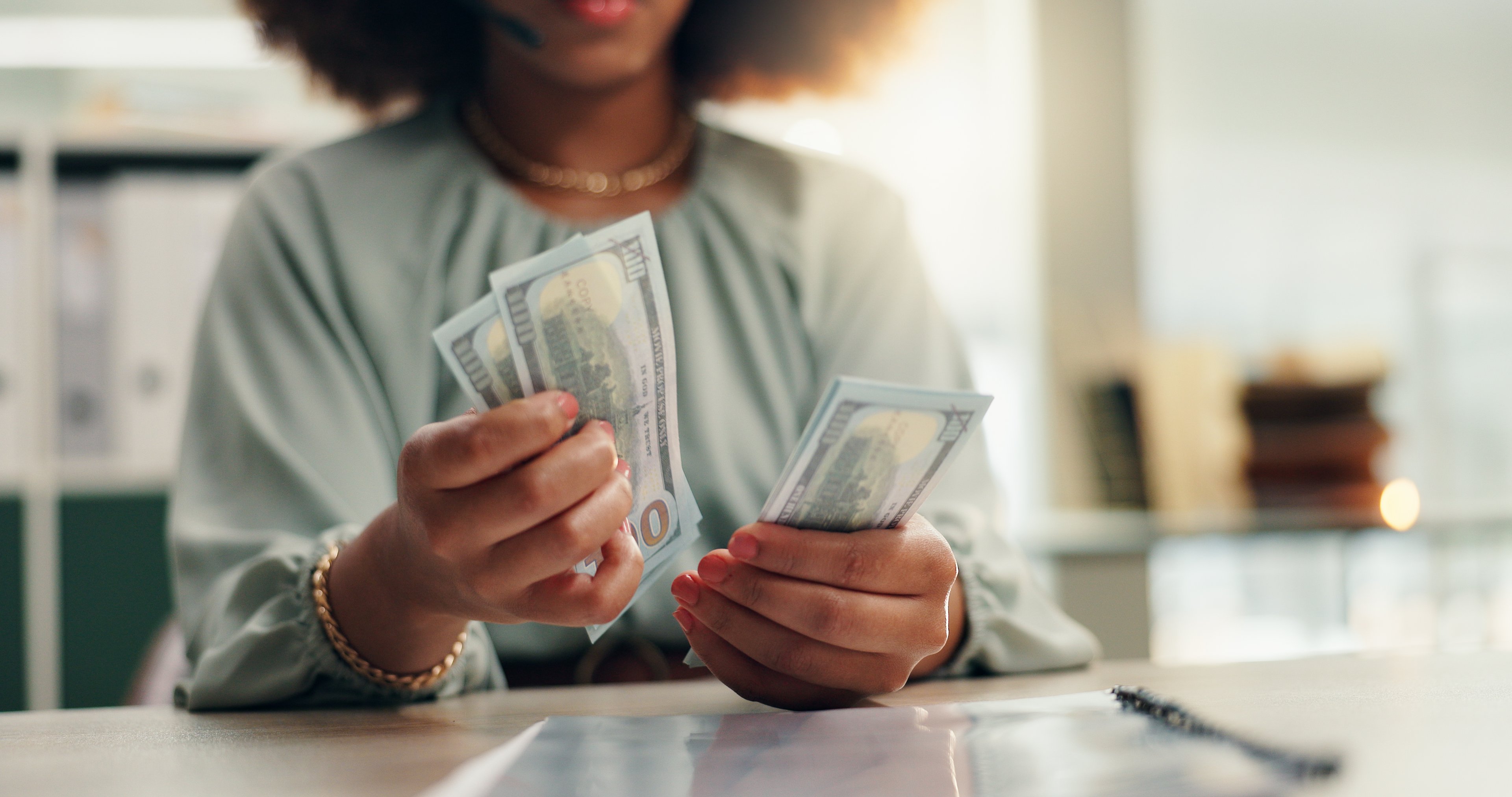 Woman counting money while sitting at a table.