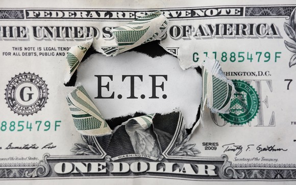 The letters "ETF" in a hole in dollar bill.