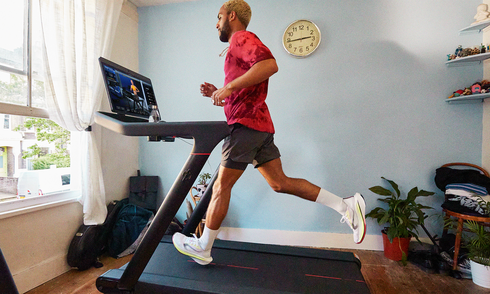 Person running on Peloton treadmill wearing shorts and a T-shirt.