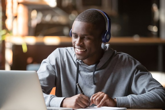 A person looking at a computer wearing headphones. 