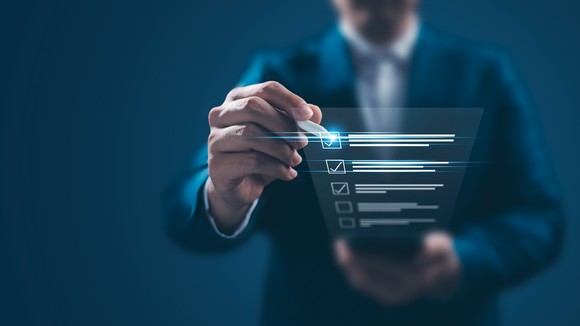 A person in a suit checks off items on a checklist. 