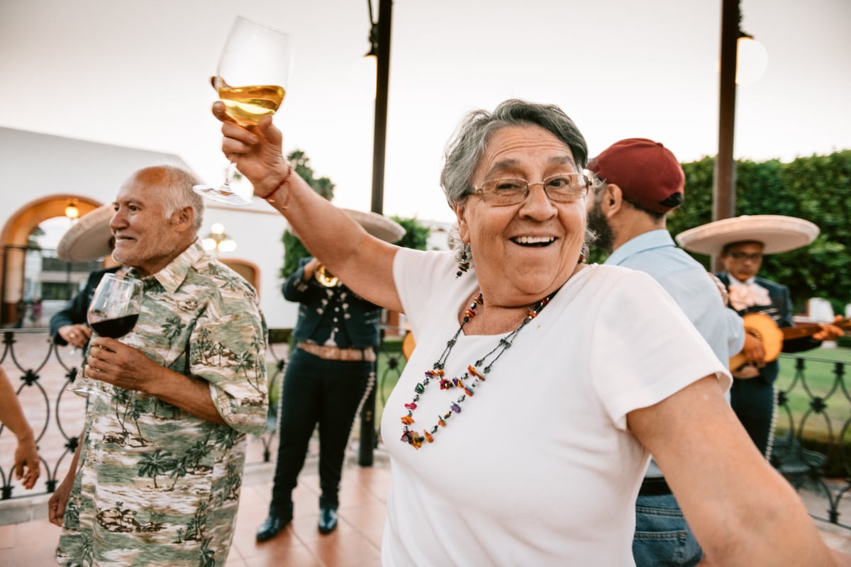 People dancing at party with wine glasses in their hands.