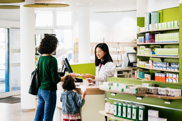 An adult and child picking up something at a pharmacy.