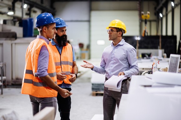 Three workers talking in a warehouse.