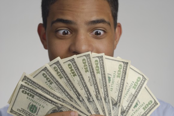 A person looking very pleased while holding and looking at $1,000 cash in 10 $100 bills.