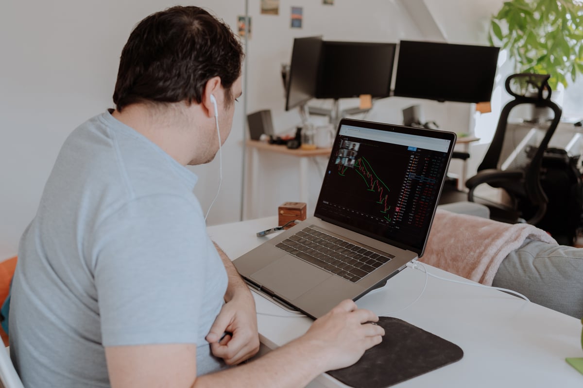A person sitting down and looking at a price chart on their laptop.