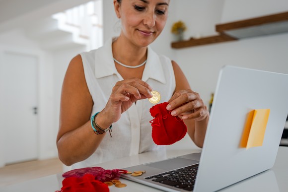 Person sitting at a computer putting money aside for savings.