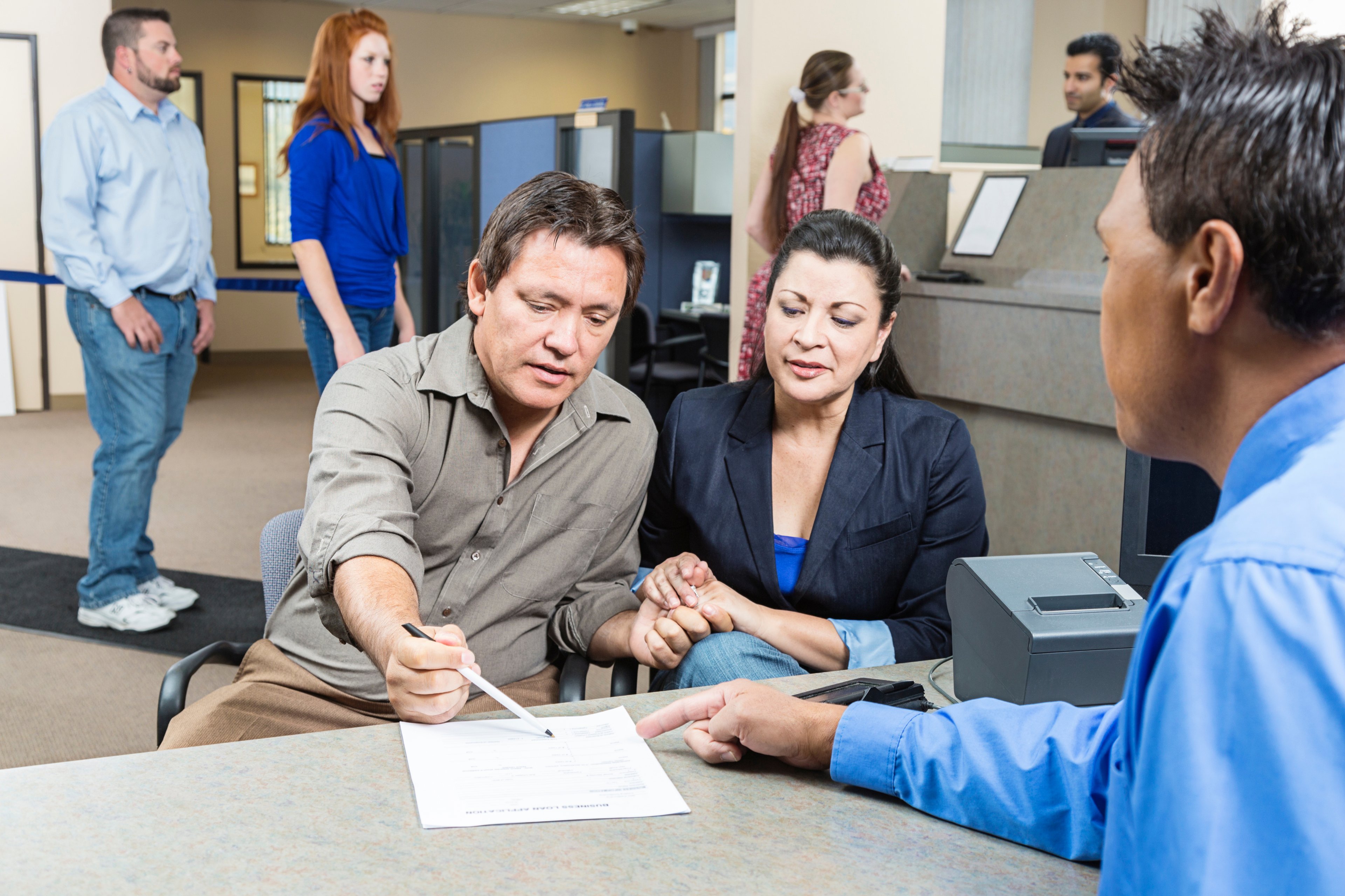 A bank employee going over loan paperwork with two prospective clients.