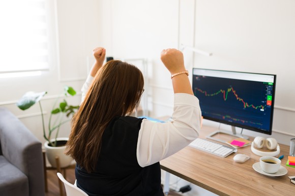 An investor cheers while looking at a stock chart displayed on a computer screen.