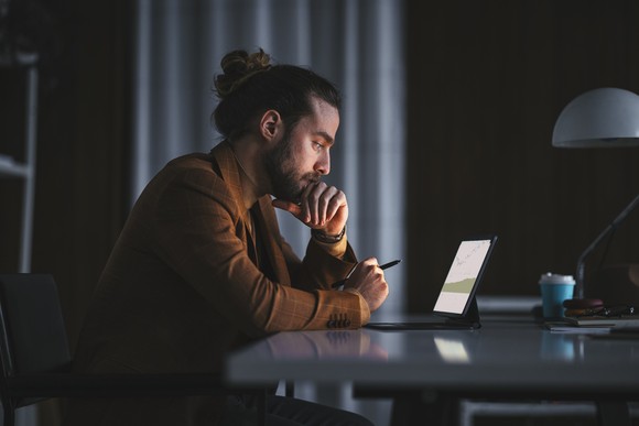 Person sitting at a desk working on a laptop. 