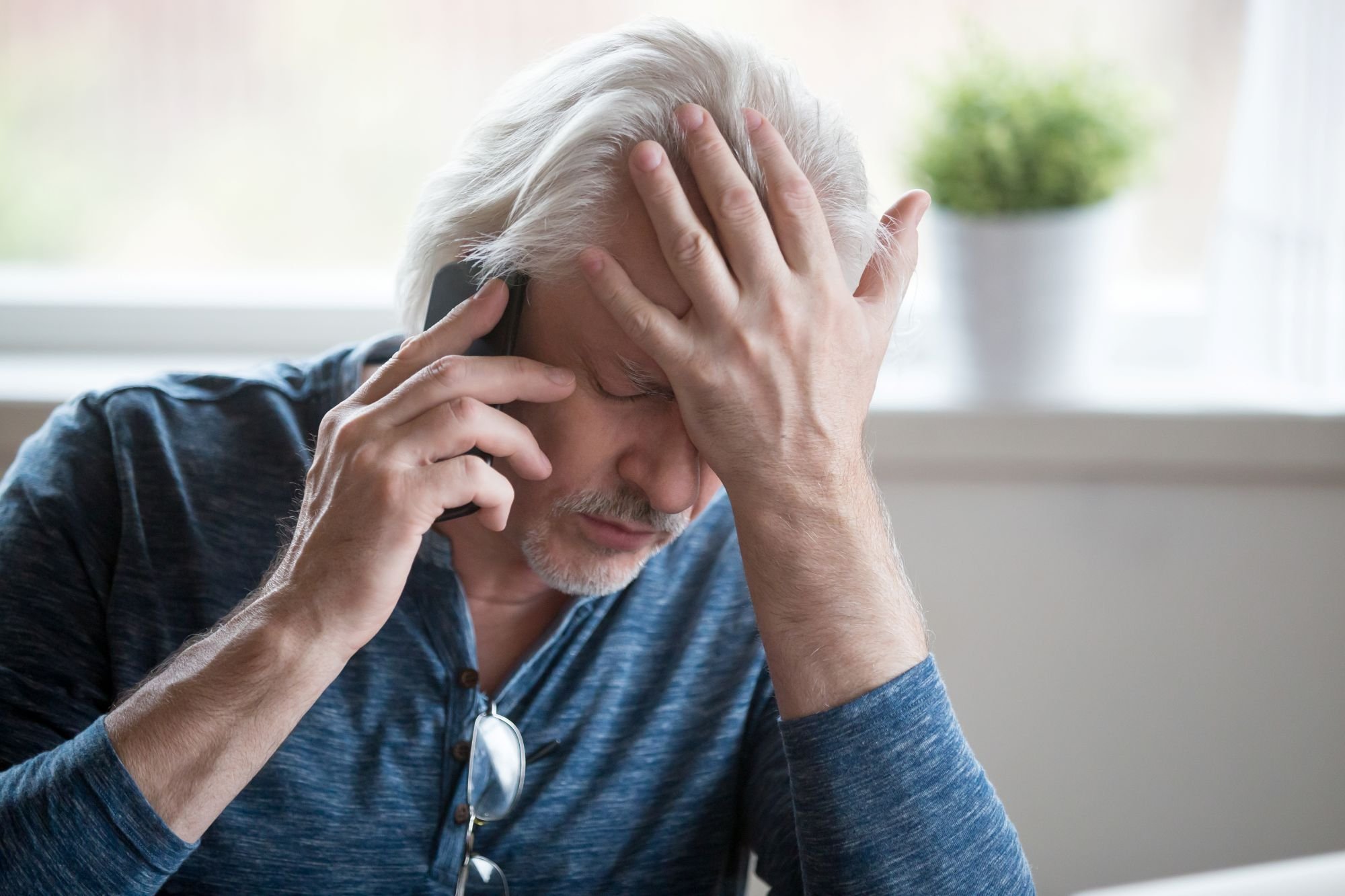Frustrated elderly person holding a cell phone.