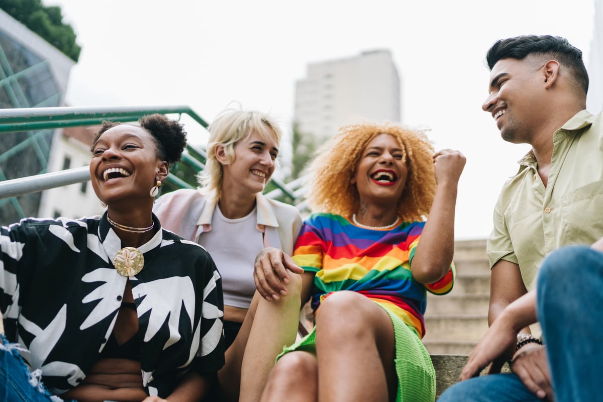 A group of four happy people sitting on steps.