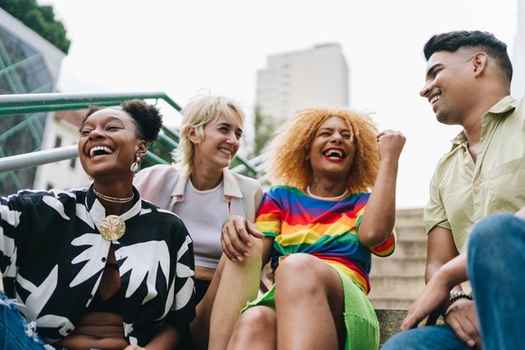 A group of four happy people sitting on steps.