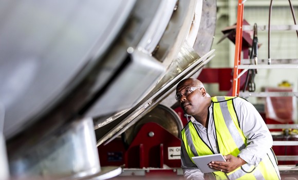 A worker inspecting machines at a steel fabrication shop. 