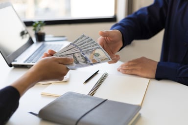 Two people exchange money at a table