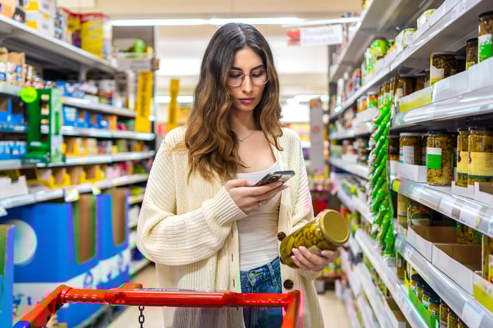 A person looks at their phone in a shopping aisle.