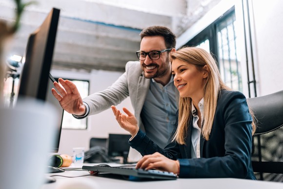 Two investors study something on a computer in an office.