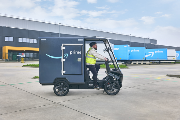 A worker drives an Amazon electric delivery bike.