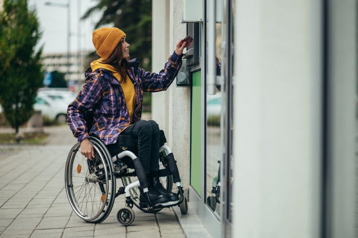 A person in a wheelchair using an ATM.