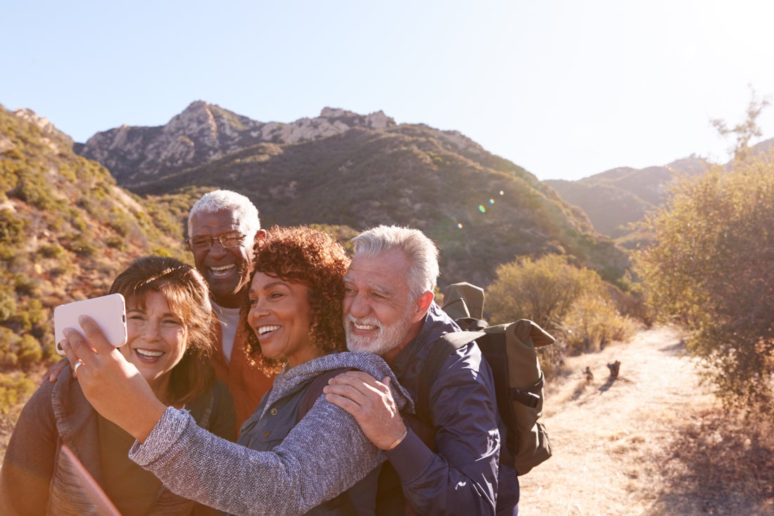 Two older couples taking a selfie as they hike through rugged terrain. 