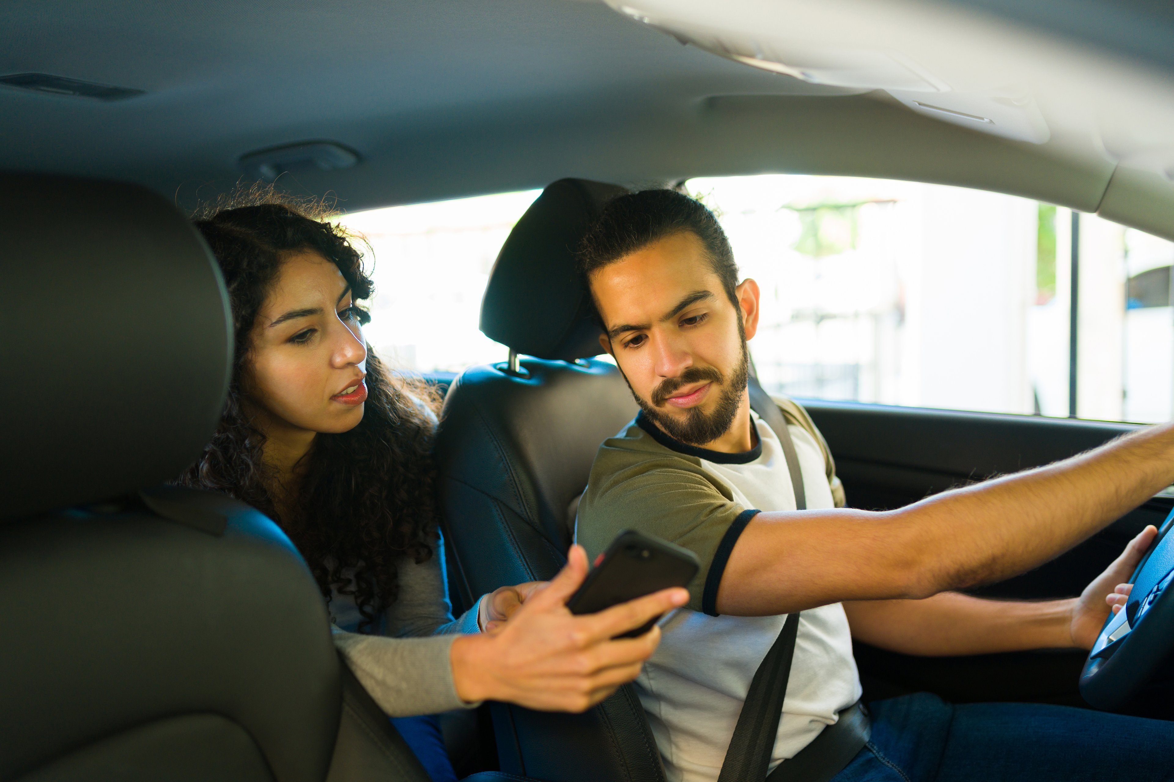 A ride-share passenger showing a driver directions on their smartphone.