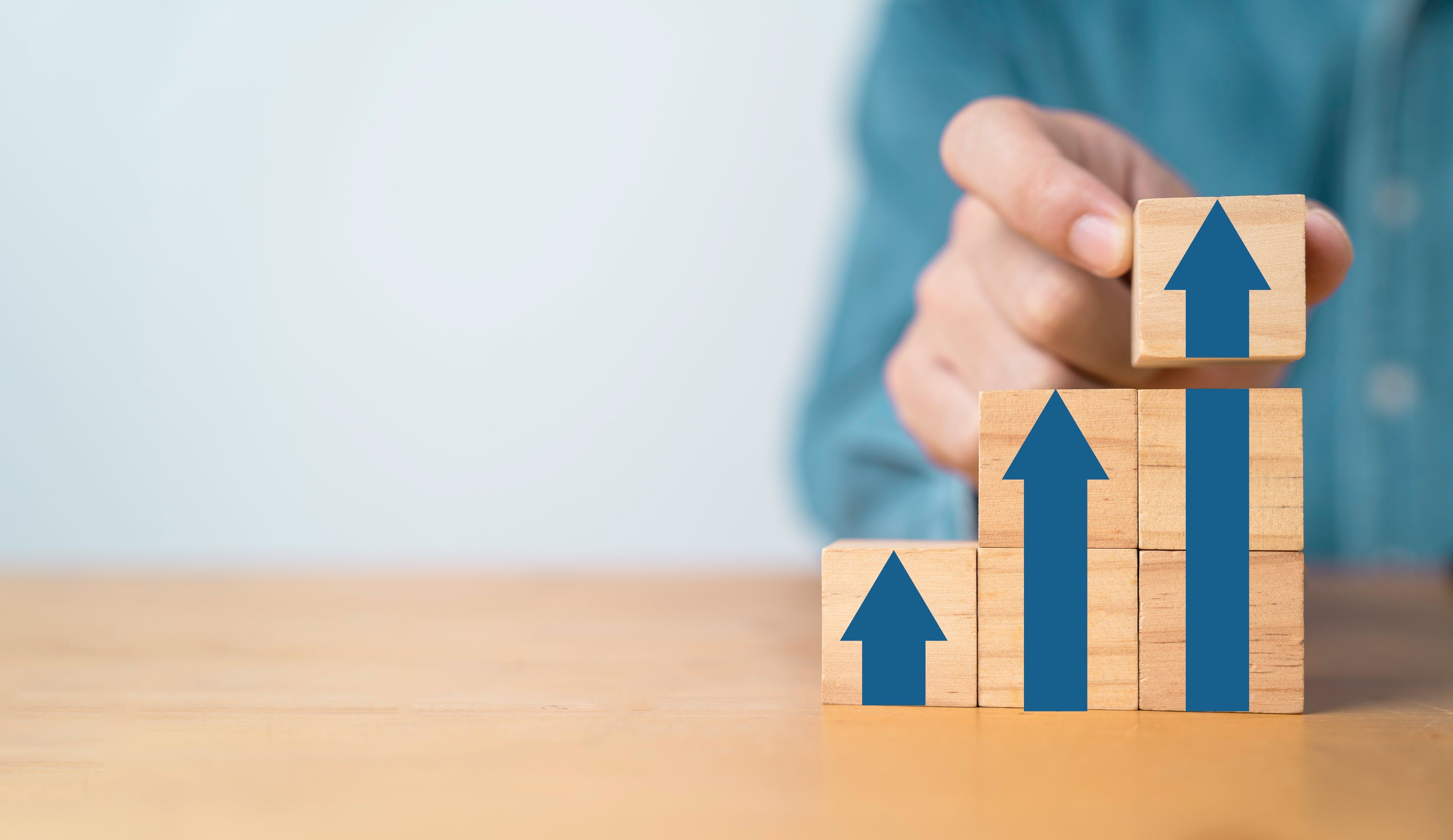 Hand stacking blocks with up arrows on them.