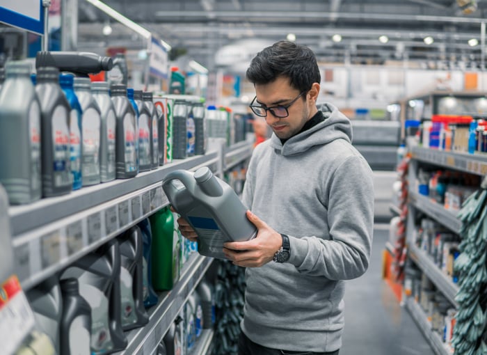 A shopper in an auto parts store looking at motor oil.