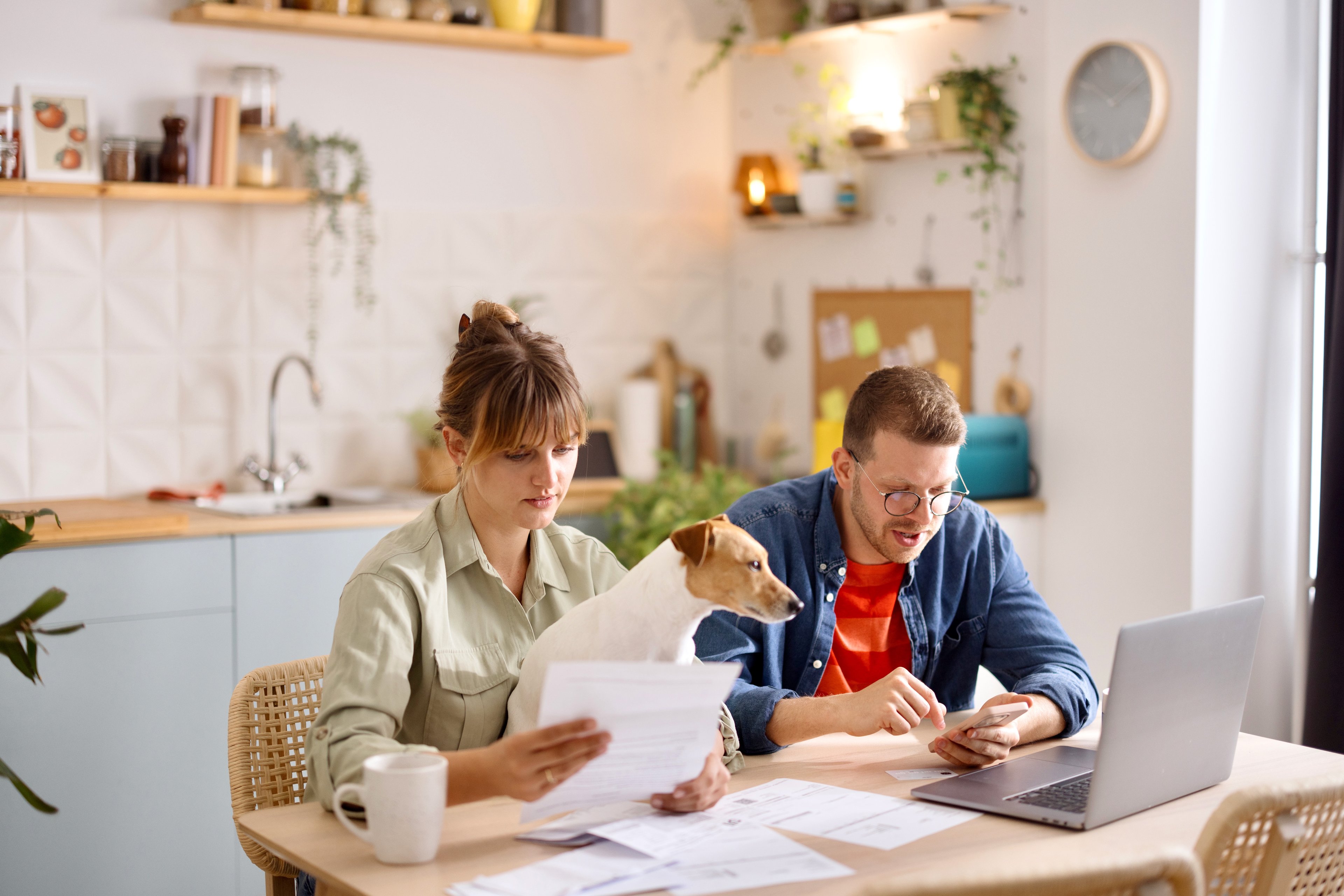 Two people sitting at a desk with a dog. 