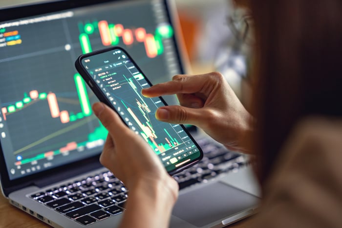 looking at stock charts on laptop and smartphone.