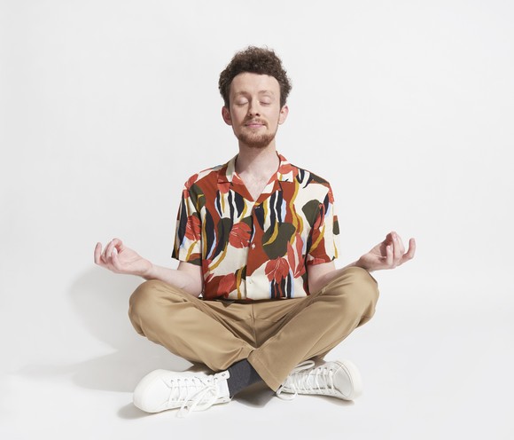 A man sitting cross legged and meditating. 